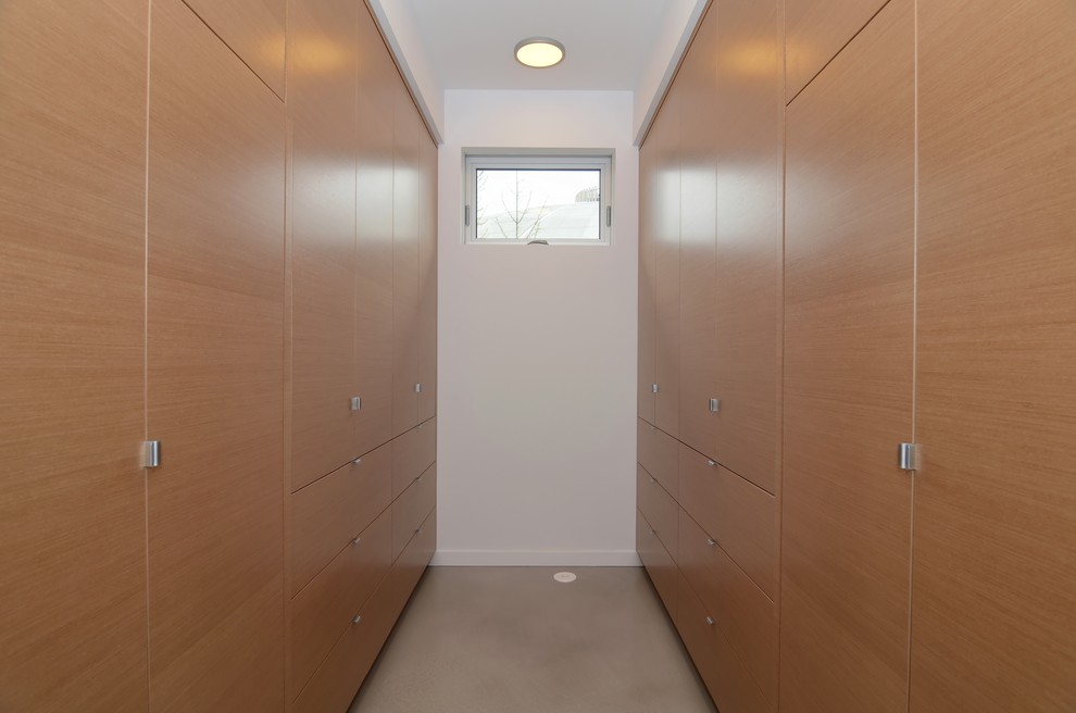 Foto de armario vestidor unisex escandinavo grande con armarios con paneles lisos, puertas de armario de madera clara y suelo de cemento