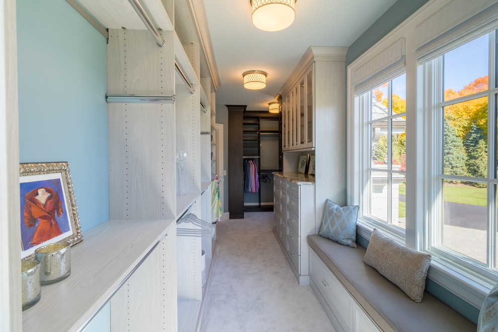 This is an example of a large classic walk-in wardrobe for women in Minneapolis with recessed-panel cabinets, light wood cabinets, carpet and grey floors.