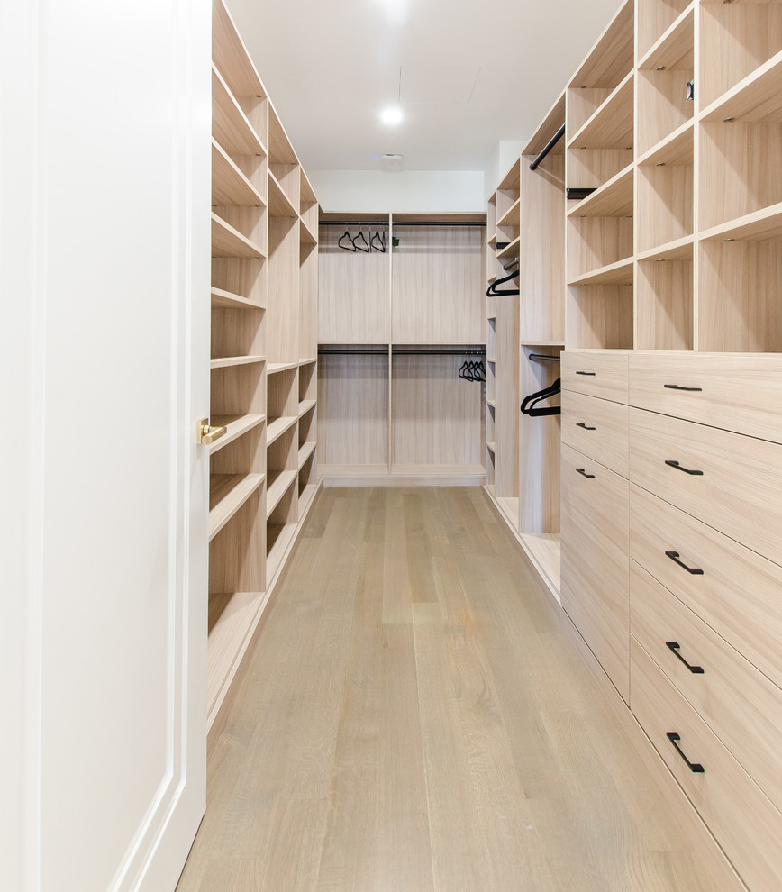 Diseño de armario vestidor unisex moderno grande con puertas de armario beige y suelo de madera clara