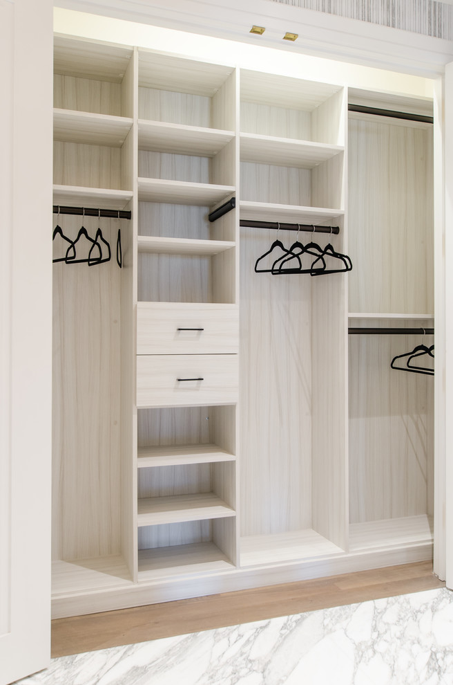 Diseño de armario unisex moderno grande con puertas de armario beige y suelo de madera clara