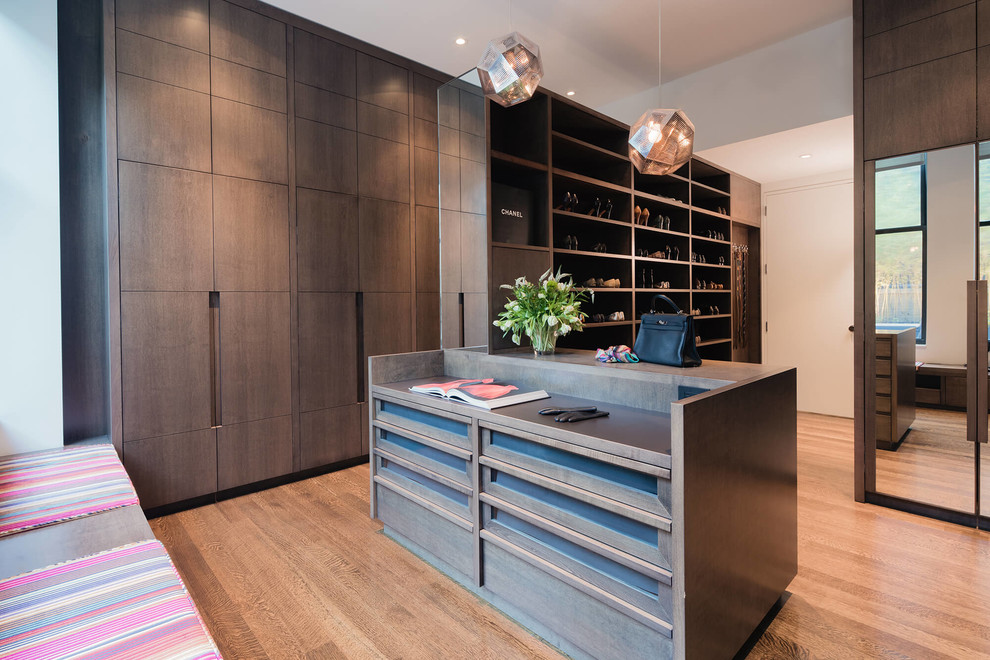 Design ideas for a large contemporary gender neutral dressing room in New York with flat-panel cabinets, brown floors, dark wood cabinets and medium hardwood flooring.