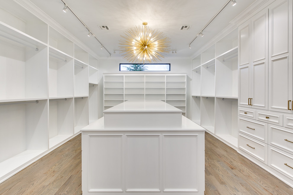 Ejemplo de armario vestidor unisex minimalista extra grande con armarios estilo shaker, puertas de armario blancas y suelo de madera en tonos medios