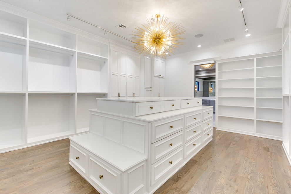 Example of a huge minimalist gender-neutral medium tone wood floor walk-in closet design in Oklahoma City with shaker cabinets and white cabinets