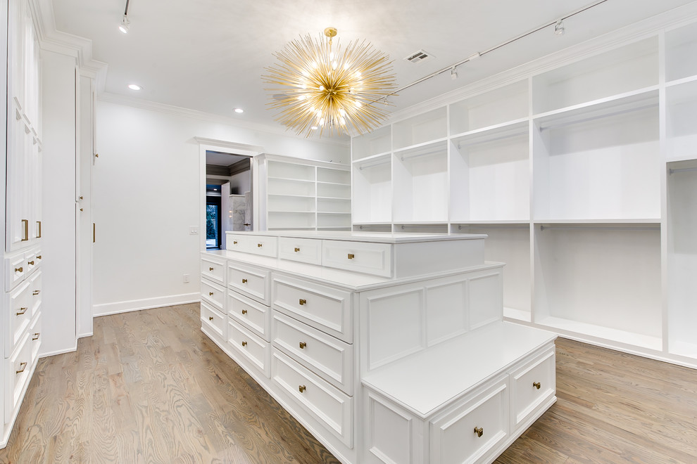 Photo of an expansive modern gender neutral walk-in wardrobe in Oklahoma City with shaker cabinets, white cabinets and medium hardwood flooring.