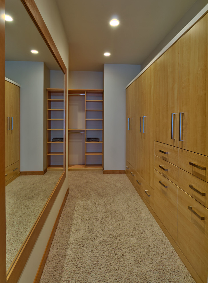 На фото: большая гардеробная комната в современном стиле с плоскими фасадами, светлыми деревянными фасадами и ковровым покрытием
