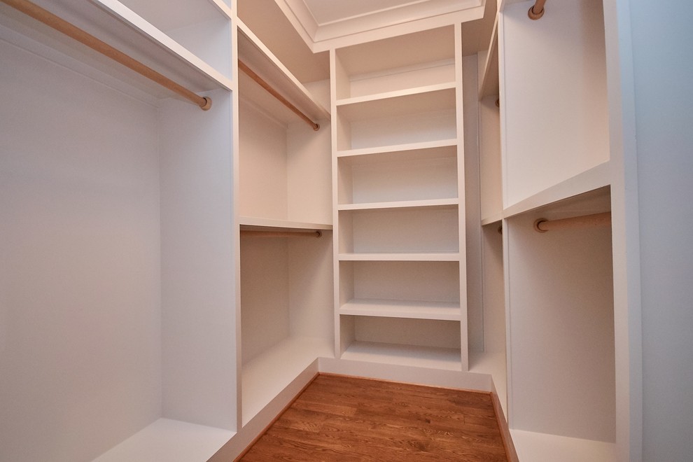 На фото: большая гардеробная комната унисекс в стиле кантри с паркетным полом среднего тона и коричневым полом с