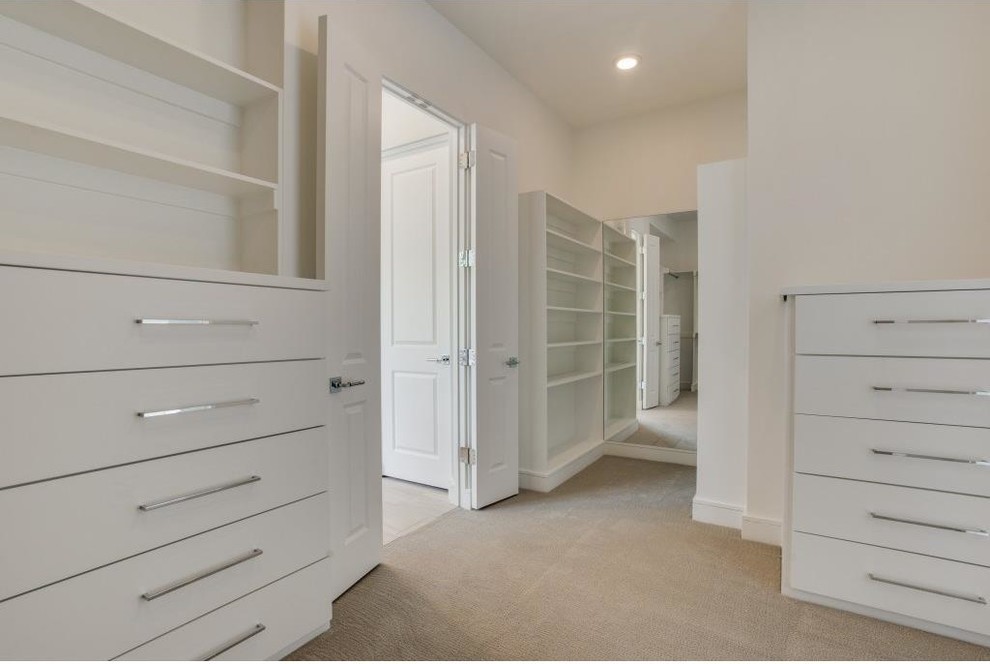 Photo of an expansive gender neutral walk-in wardrobe in Dallas with flat-panel cabinets, white cabinets and carpet.