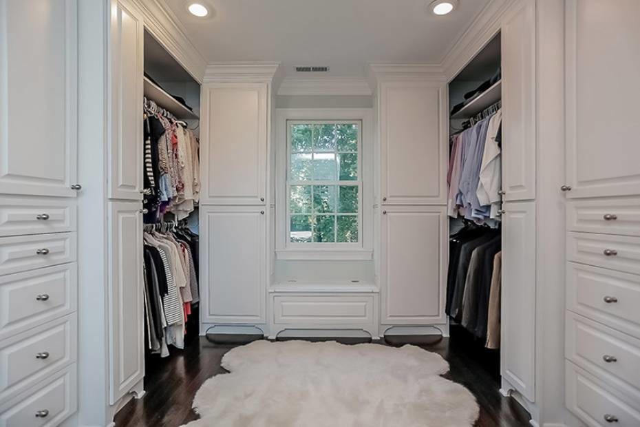 Foto de vestidor unisex de estilo americano grande con armarios con paneles con relieve, puertas de armario blancas y suelo de madera oscura
