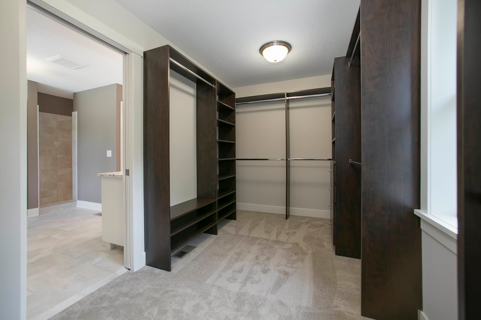 Imagen de armario vestidor unisex pequeño con puertas de armario de madera en tonos medios y moqueta