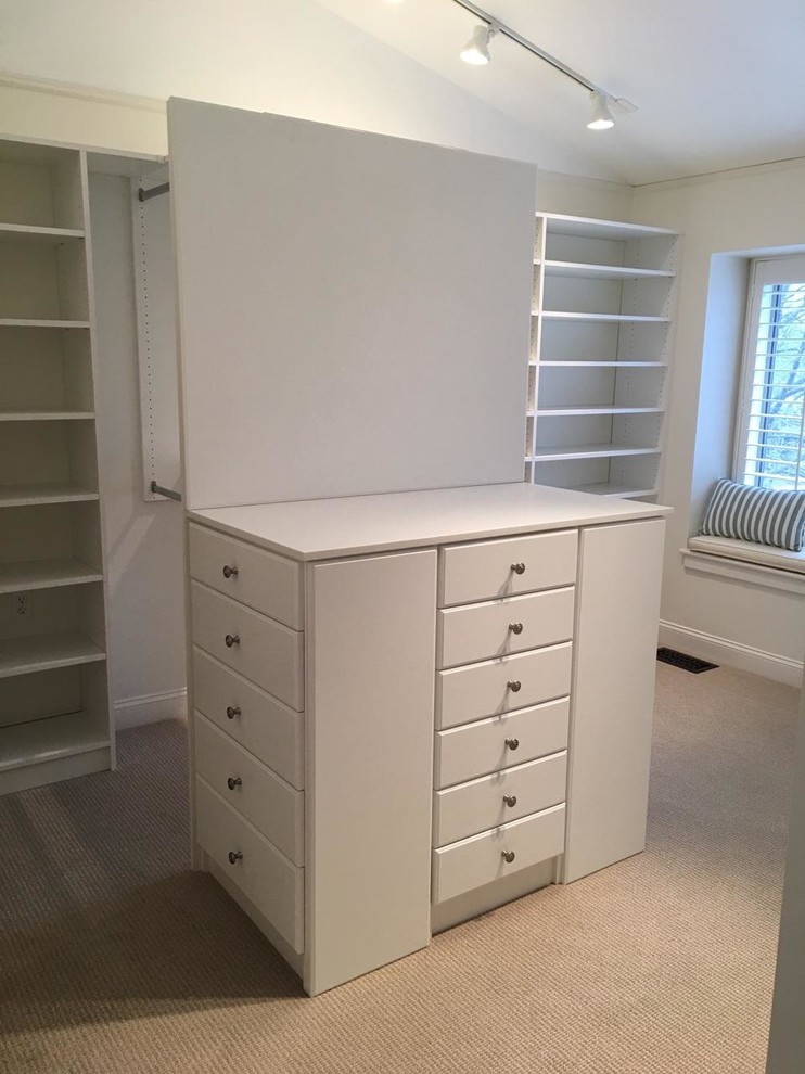 This is an example of a large contemporary gender neutral walk-in wardrobe with flat-panel cabinets, white cabinets, carpet and beige floors.