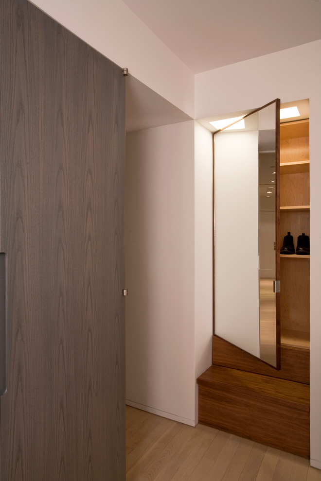 This is an example of a contemporary standard wardrobe in New York with flat-panel cabinets and dark wood cabinets.