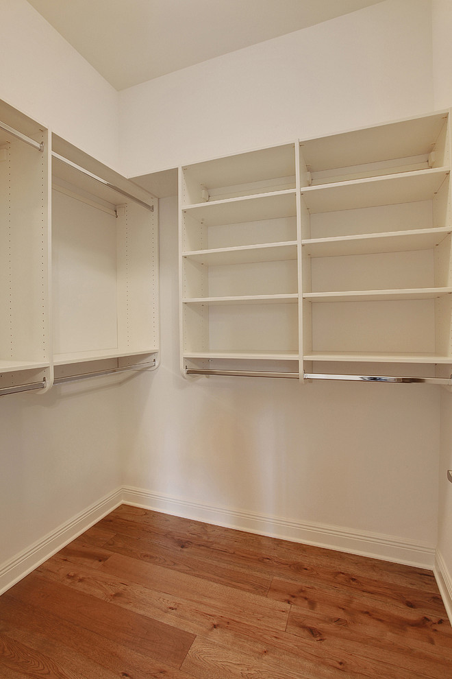 Elegant gender-neutral walk-in closet photo in New Orleans with white cabinets
