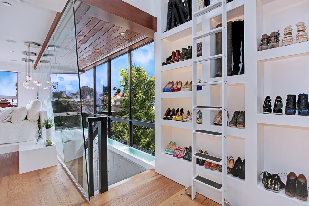 Foto de armario y vestidor actual con armarios abiertos, puertas de armario blancas y suelo de madera clara