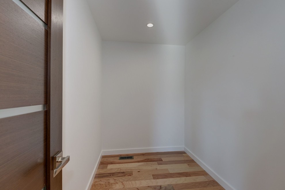Imagen de vestidor unisex actual de tamaño medio con suelo de madera clara
