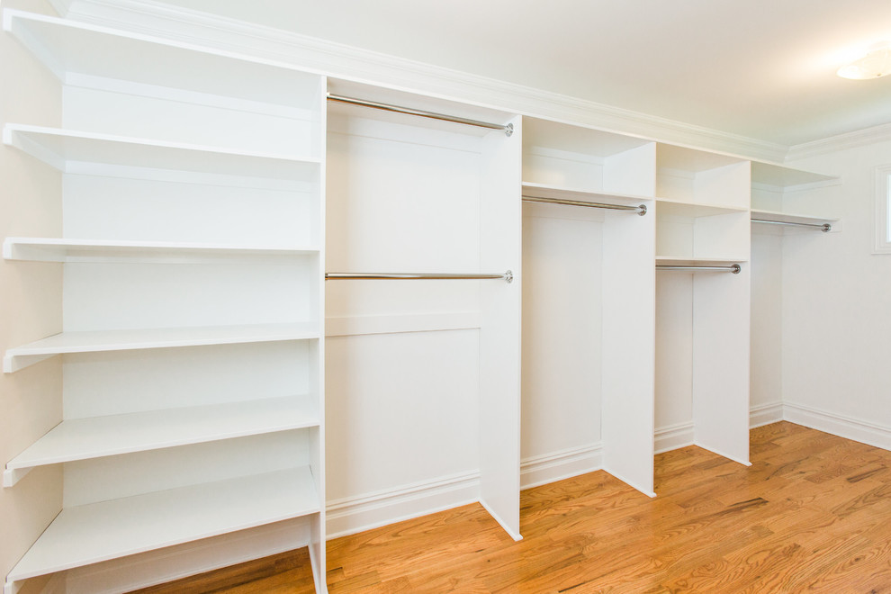 Diseño de armario vestidor unisex tradicional de tamaño medio con armarios abiertos, puertas de armario blancas, suelo de madera en tonos medios y suelo marrón