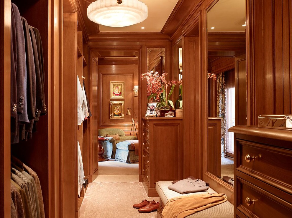 Large elegant men's carpeted and beige floor walk-in closet photo with dark wood cabinets and recessed-panel cabinets