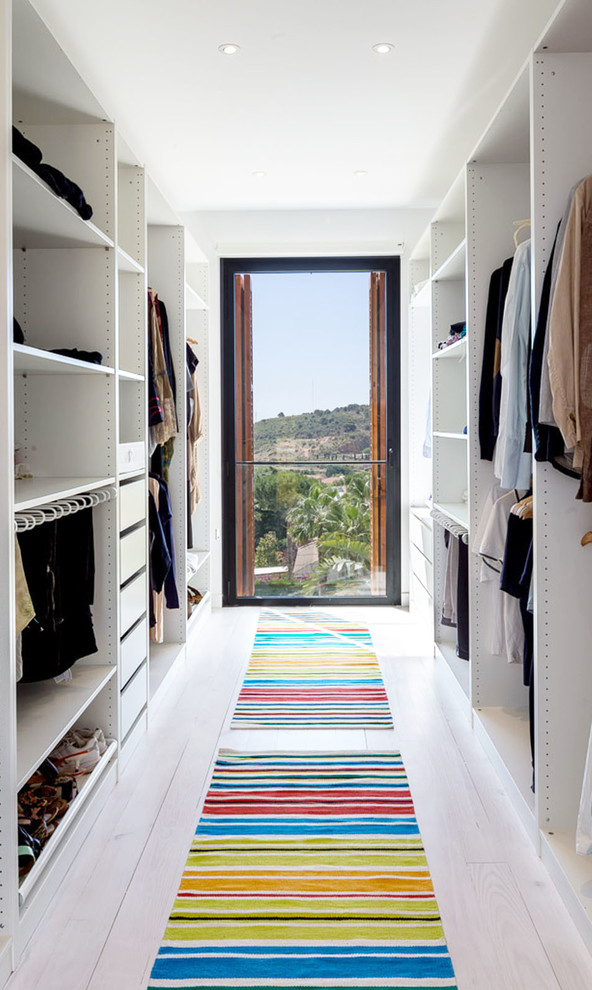 Medium sized modern gender neutral walk-in wardrobe in Barcelona with open cabinets, white cabinets and light hardwood flooring.