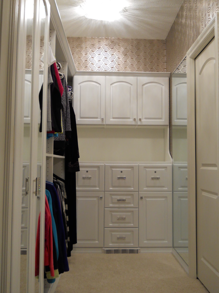 Ejemplo de armario vestidor de mujer actual grande con armarios con paneles con relieve, puertas de armario blancas y moqueta