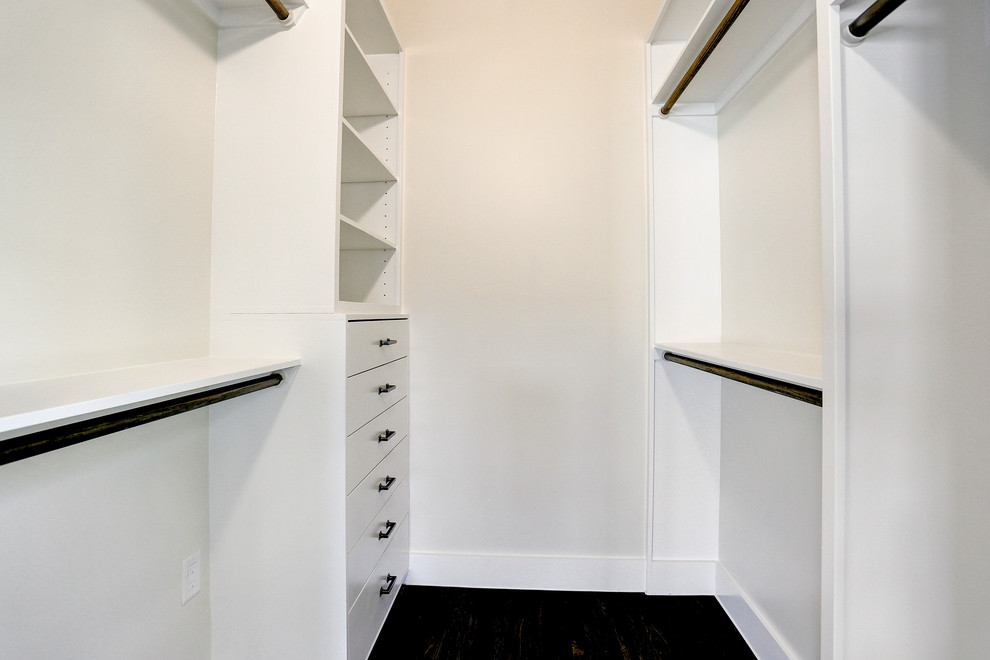Amerikansk inredning av ett litet walk-in-closet för könsneutrala, med luckor med infälld panel, vita skåp, mörkt trägolv och brunt golv