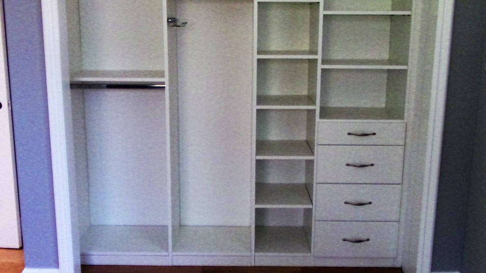 Ejemplo de armario unisex contemporáneo de tamaño medio con armarios con paneles lisos, puertas de armario blancas, suelo de madera en tonos medios y suelo marrón