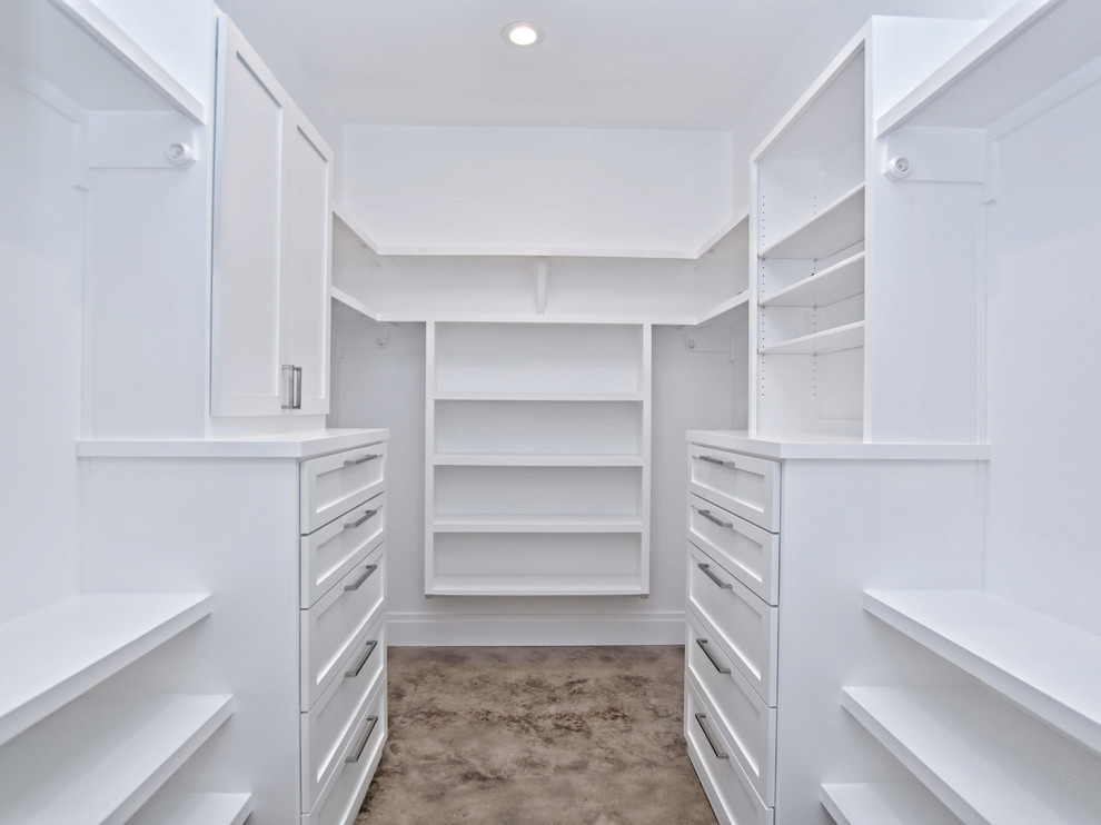 Inredning av ett klassiskt stort walk-in-closet, med öppna hyllor, vita skåp, betonggolv och brunt golv