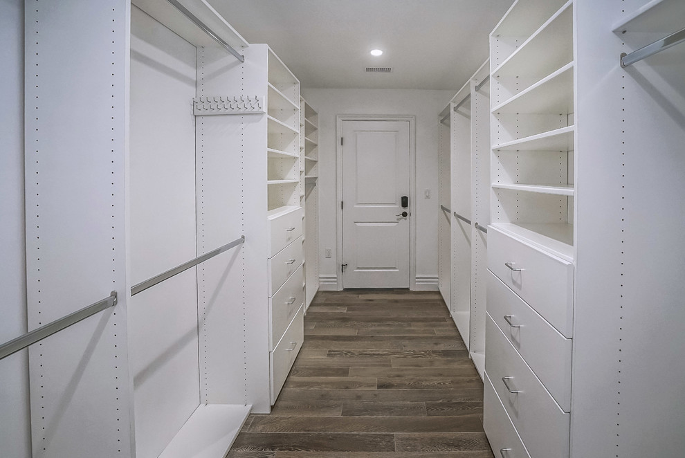 Ejemplo de armario vestidor unisex retro de tamaño medio con armarios con paneles lisos, puertas de armario blancas, suelo de madera oscura y suelo marrón