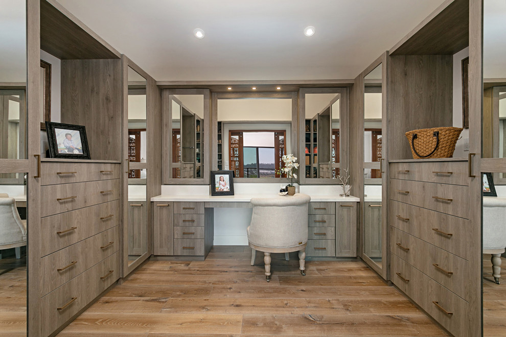 Exemple d'un dressing room tendance en bois brun avec un placard à porte plane et un sol en bois brun.