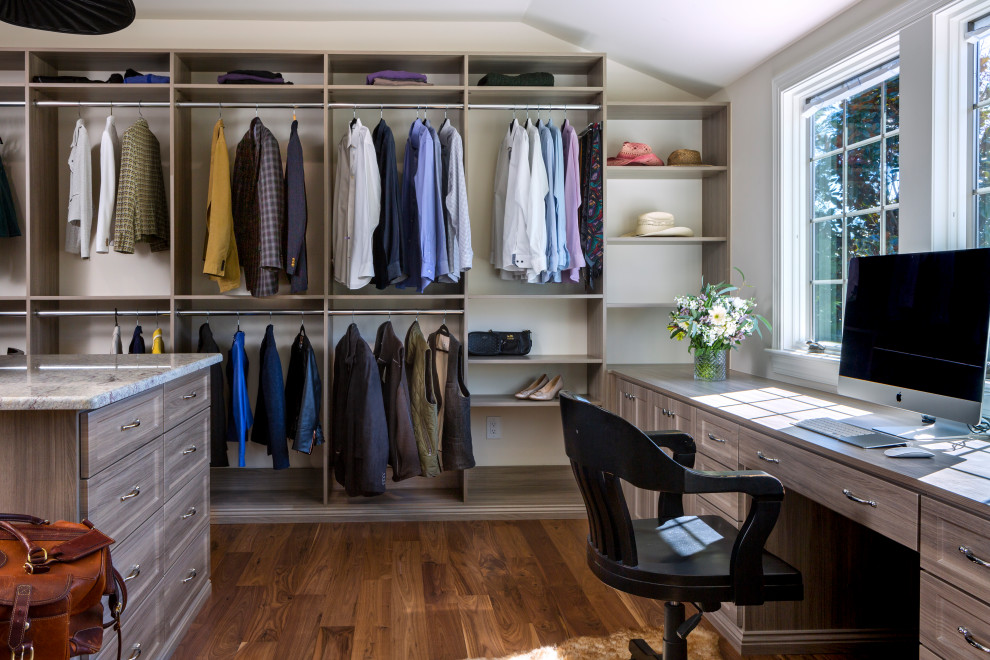 На фото: гардеробная комната унисекс в стиле неоклассика (современная классика) с открытыми фасадами, серыми фасадами, темным паркетным полом и коричневым полом с
