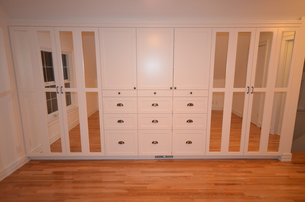 Imagen de armario y vestidor tradicional con armarios estilo shaker, puertas de armario blancas y suelo de madera clara