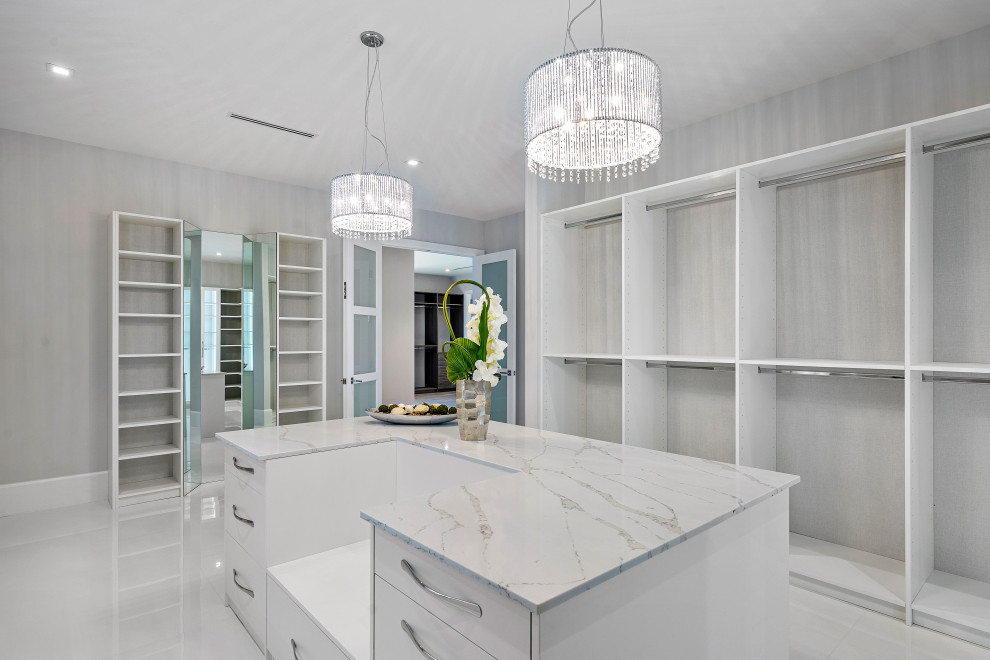 Trendy gender-neutral marble floor and white floor built-in closet photo in Miami with open cabinets and white cabinets