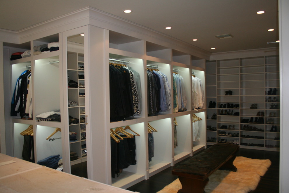 Ejemplo de armario vestidor unisex moderno grande con armarios abiertos, puertas de armario blancas y suelo de madera oscura