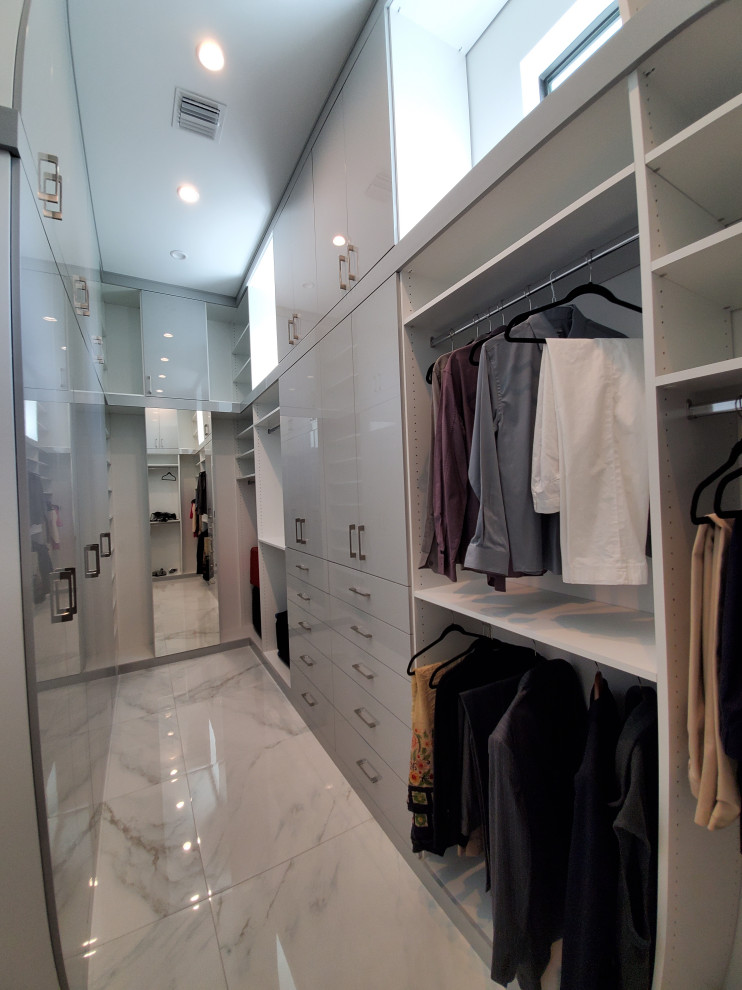 Idéer för att renovera ett stort funkis walk-in-closet för könsneutrala, med släta luckor, vita skåp, marmorgolv och vitt golv