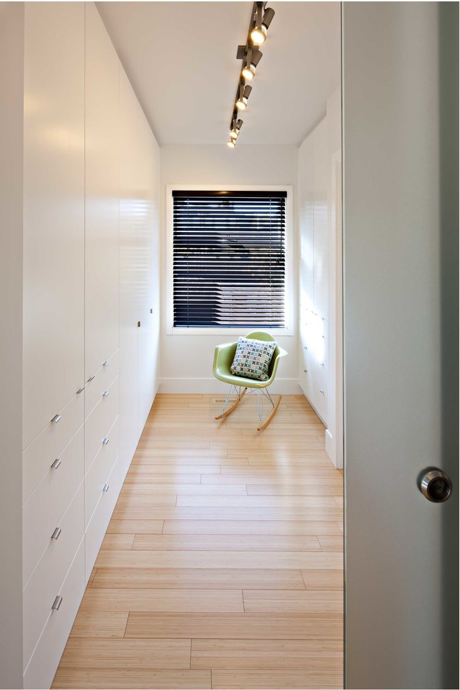 Modern inredning av ett litet walk-in-closet för könsneutrala, med släta luckor, vita skåp, ljust trägolv och beiget golv