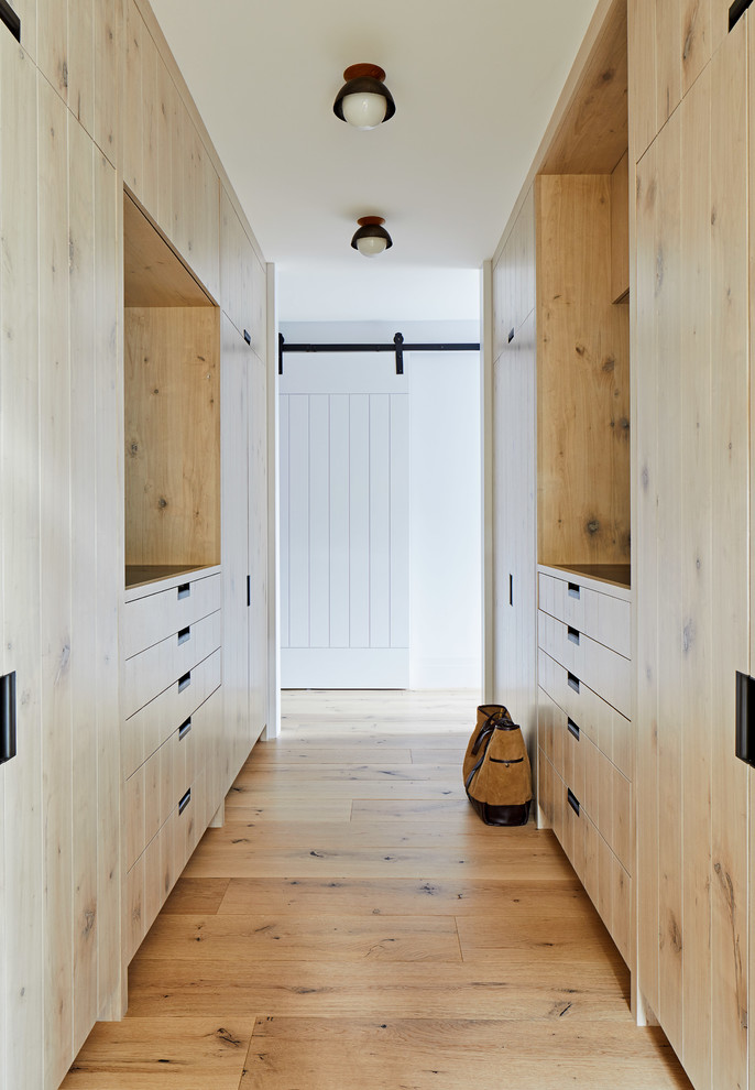 Стильный дизайн: гардеробная комната унисекс в морском стиле с плоскими фасадами, светлыми деревянными фасадами и светлым паркетным полом - последний тренд