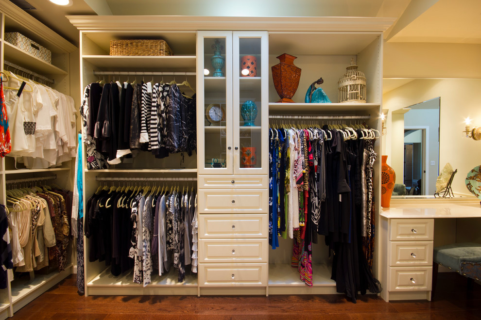 Imagen de armario vestidor de mujer clásico grande con armarios con paneles con relieve, puertas de armario blancas y suelo de madera oscura