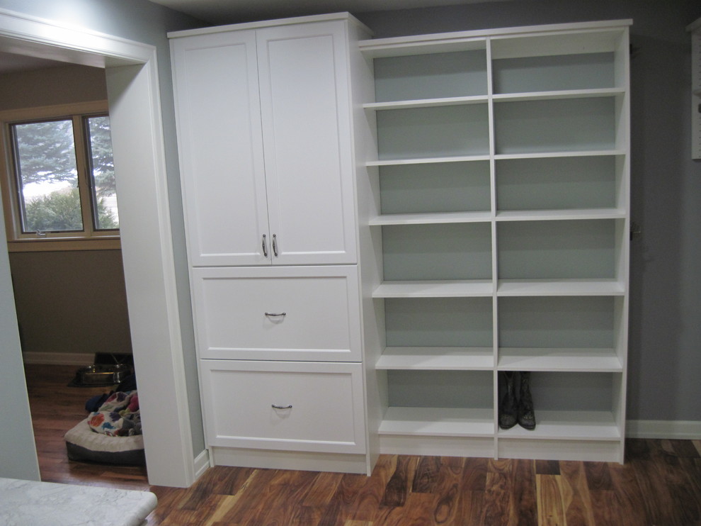 Diseño de armario vestidor unisex clásico de tamaño medio con armarios abiertos, puertas de armario blancas y suelo de madera oscura