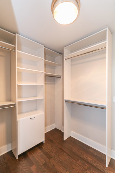 Example of a large arts and crafts gender-neutral medium tone wood floor walk-in closet design in Chicago with flat-panel cabinets and white cabinets