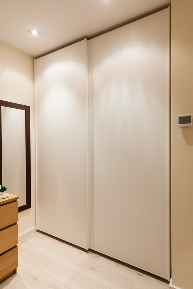 Inspiration for a medium sized contemporary gender neutral standard wardrobe in Barcelona with flat-panel cabinets, white cabinets and light hardwood flooring.