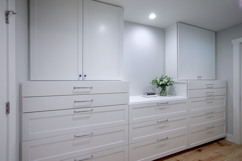 Ejemplo de armario vestidor unisex clásico renovado pequeño con armarios con paneles empotrados, puertas de armario blancas y suelo de madera clara