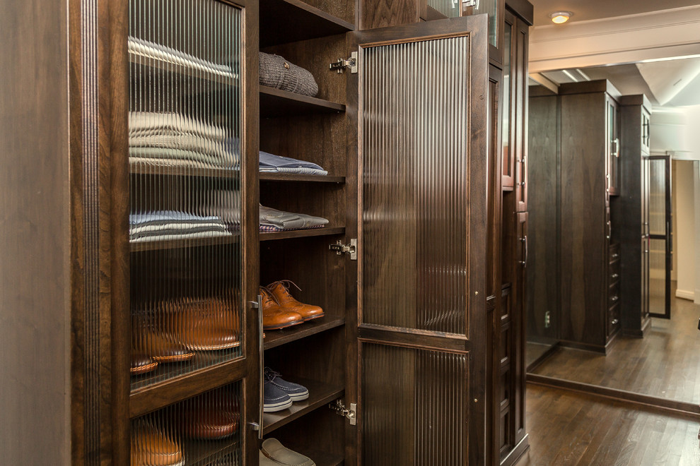 Ejemplo de vestidor unisex de estilo americano grande con armarios estilo shaker, puertas de armario de madera en tonos medios, suelo de madera en tonos medios y suelo marrón