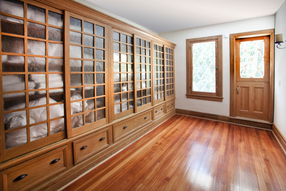 Reach-in closet - traditional reach-in closet idea in New York with glass-front cabinets and medium tone wood cabinets