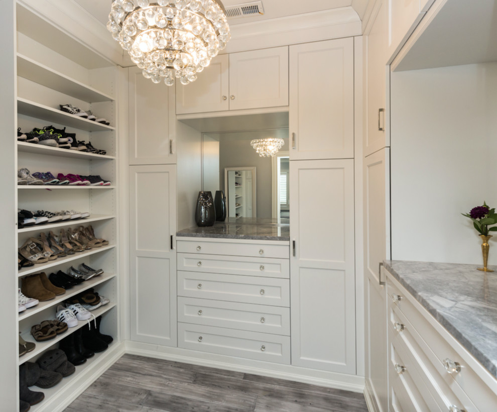 Imagen de armario vestidor unisex minimalista grande con armarios con paneles empotrados, puertas de armario blancas, suelo de madera en tonos medios y suelo gris