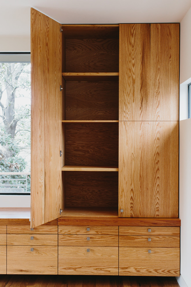 Walk-in closet - mid-sized modern gender-neutral medium tone wood floor walk-in closet idea in Atlanta with flat-panel cabinets and medium tone wood cabinets