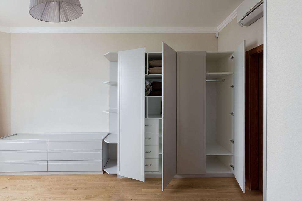 Imagen de armario y vestidor actual de tamaño medio con suelo de madera clara