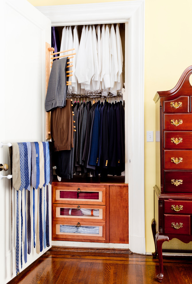 Design ideas for a small classic gender neutral standard wardrobe in New York with glass-front cabinets, medium wood cabinets, medium hardwood flooring and brown floors.