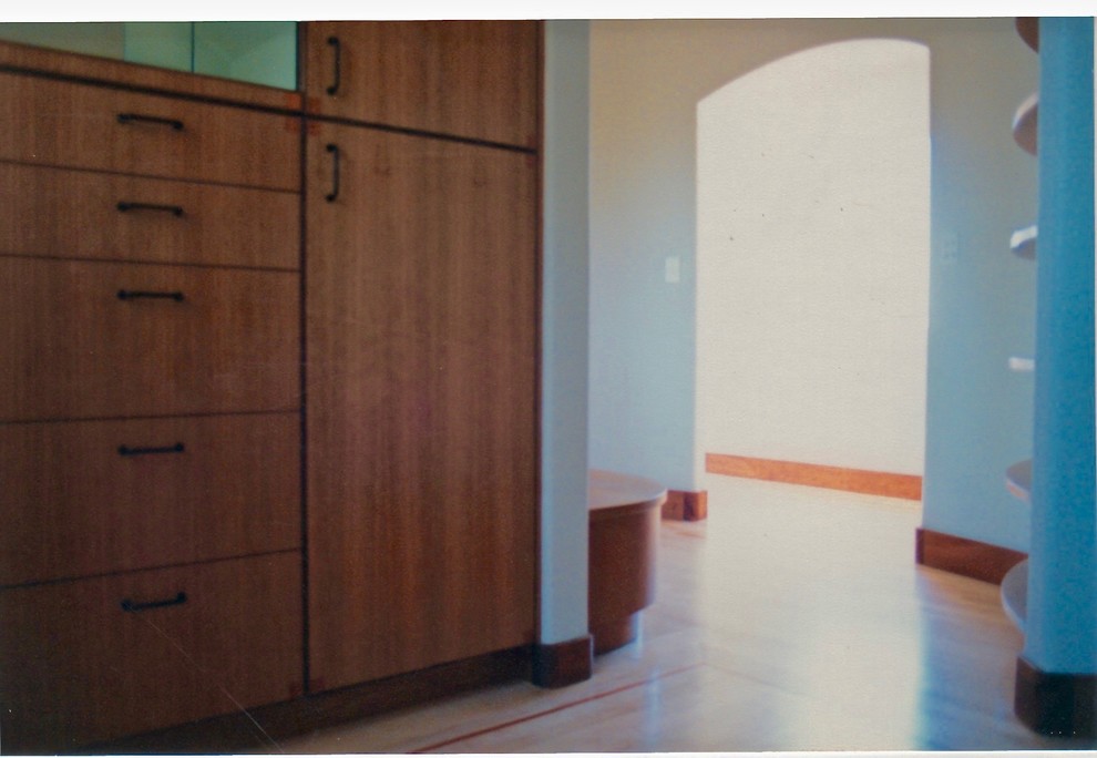 Imagen de vestidor de hombre contemporáneo grande con armarios con paneles lisos, puertas de armario de madera oscura y suelo de madera clara