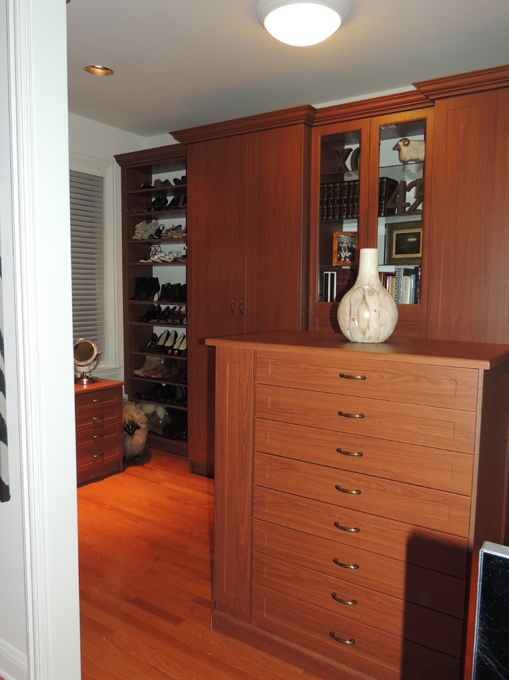 Idée de décoration pour un dressing room design en bois brun de taille moyenne pour une femme avec un placard avec porte à panneau encastré.