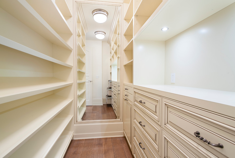 Walk-in closet - traditional gender-neutral medium tone wood floor walk-in closet idea in Vancouver with raised-panel cabinets and distressed cabinets