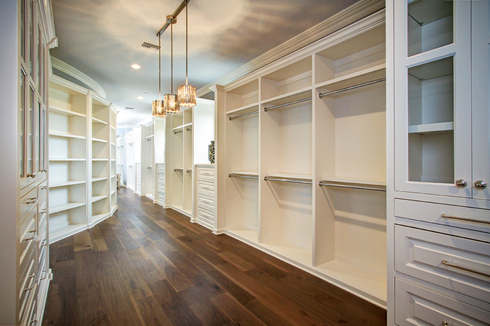Ejemplo de armario vestidor unisex clásico renovado extra grande con armarios con paneles con relieve, puertas de armario blancas y suelo de madera oscura