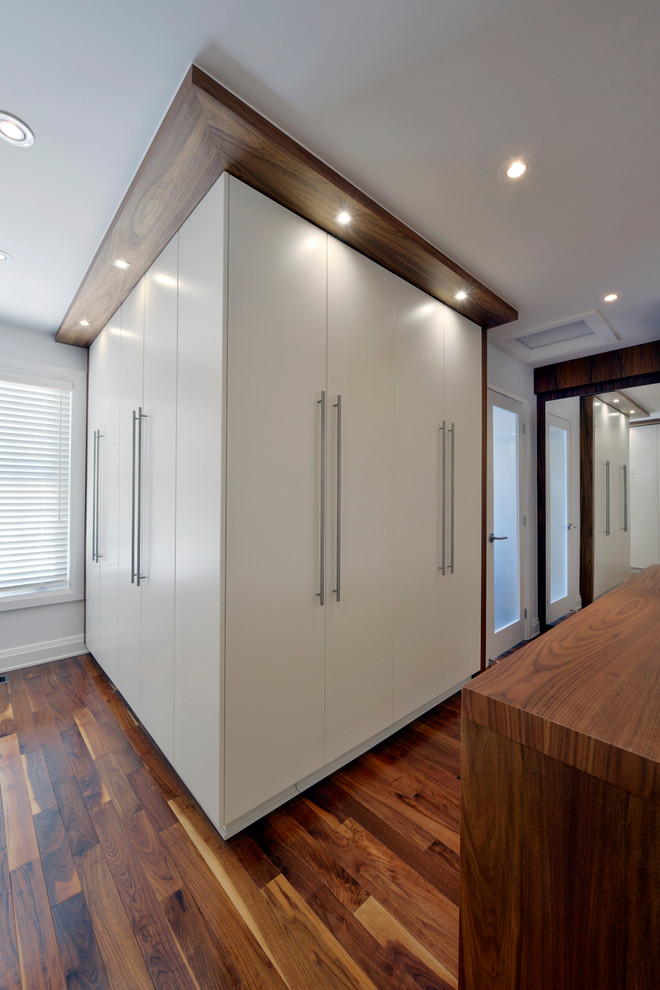 Inspiration for a large contemporary gender neutral walk-in wardrobe in Ottawa with flat-panel cabinets, white cabinets and dark hardwood flooring.